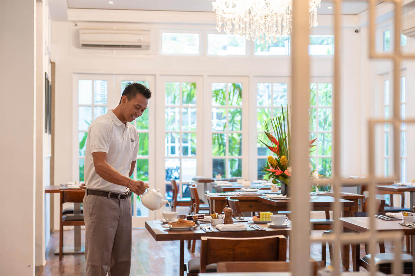 a waiter pours tea into a cup at the colony hotel seminyak